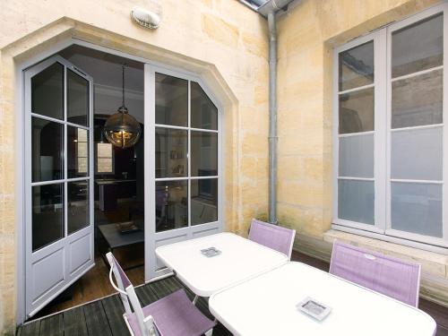 - deux tables et des chaises sur une terrasse avec fenêtres dans l'établissement Bord'ôappart Le Cheverus, à Bordeaux