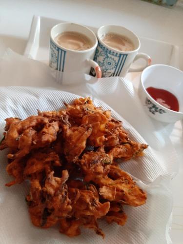 a plate of food with two cups of coffee at Katihalli Estate Stays in Hassan