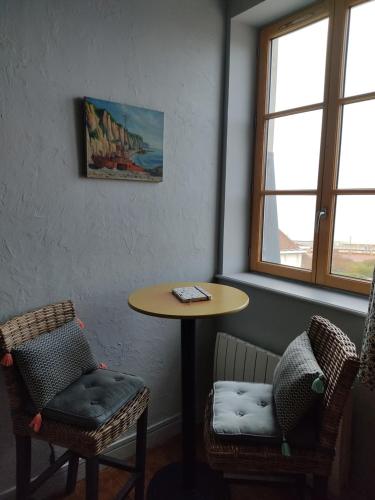 a table and chairs in a room with a table and two windows at résidence des bains in Veules-les-Roses