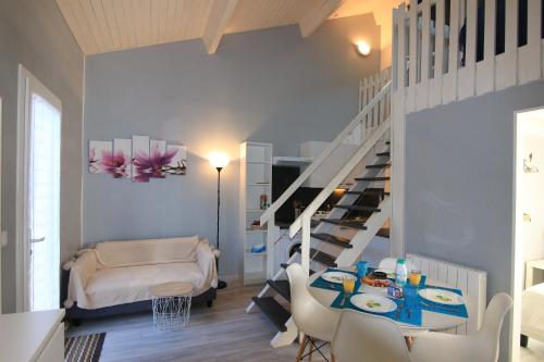 ein Wohnzimmer mit einer Treppe, einem Tisch und Stühlen in der Unterkunft Appartement SOULAC SUR MER À 500 m de la plage N 3 in Soulac-sur-Mer