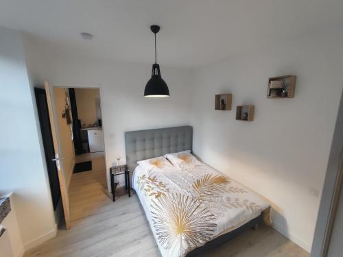 uma pequena cama num quarto com uma parede branca em Appartement T2 "Le Cocoön" rez-de-jardin au calme em Vitré