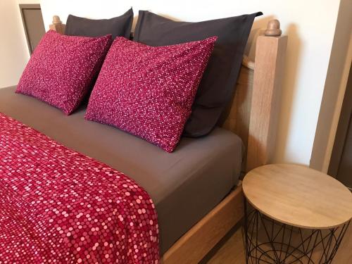 1 cama con 2 almohadas rosas y mesa en Logement cosy à Durbuy, en Durbuy