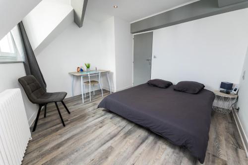 une chambre avec un lit, une chaise et une table dans l'établissement Dormir A6 - Dormir Comme A La Maison -, à Châteaubriant