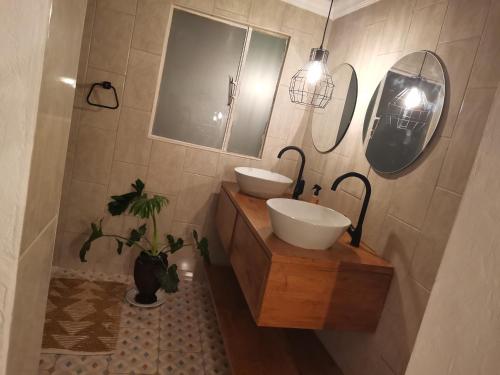 a bathroom with two sinks and a mirror and a plant at Bono Luxury Guesthouse in Rustenburg