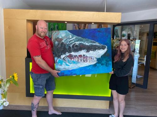 a man and a woman holding a painting of a shark at Hotel am Müritz-Nationalpark in Waren