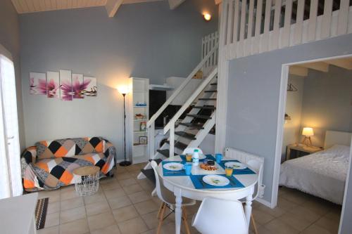 a living room with a table and a staircase at Appartement SOULAC SUR MER À 500 m de la plage N 7 in Soulac-sur-Mer