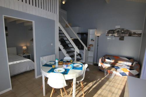 a living room with a table and chairs and a staircase at Appartement villa Oceanides 500m de la plage N 8 in Soulac-sur-Mer