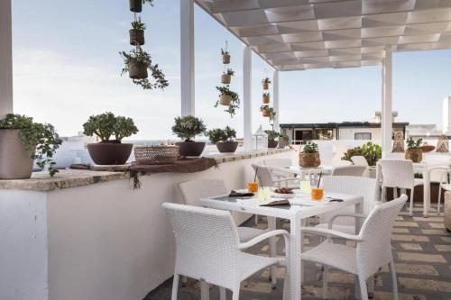 a patio with white tables and chairs and potted plants at Faro Bianco Gallipoli - Suites & Apartments in Gallipoli