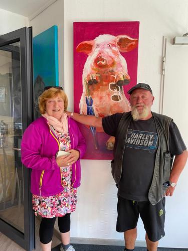 a man and woman standing in front of a painting of a cow at Hotel am Müritz-Nationalpark in Waren