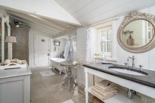 ein Badezimmer mit einem Waschbecken, einem Spiegel und einer Badewanne in der Unterkunft Guesthouse B&B De Loverlij in Jabbeke