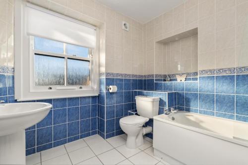 a blue tiled bathroom with a toilet and a sink at Top Sail - Beautiful Apartment, Minutes Walk to Beach and Town Centre in Tenby