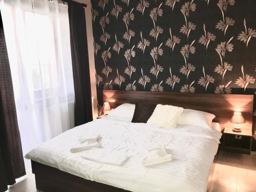 a bedroom with a white bed with a floral wallpaper at FeEl Tatras Direct View apartment in Veľká Lomnica