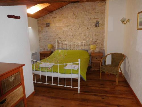 ein Schlafzimmer mit einem Bett mit einer grünen Bettdecke und einem Stuhl in der Unterkunft Chatenet self catering stone House for 2 South West France in Limalonges