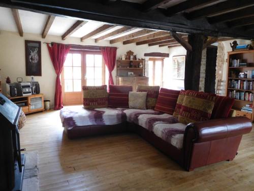 a living room with a leather couch and some windows at Chatenet self catering stone House for 2 South West France in Limalonges