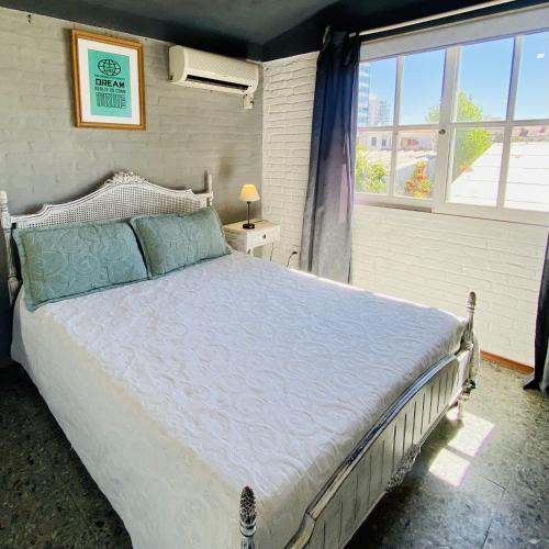 a bedroom with a large bed and a window at PASTORA Suites & Hostel - Punta del este in Punta del Este