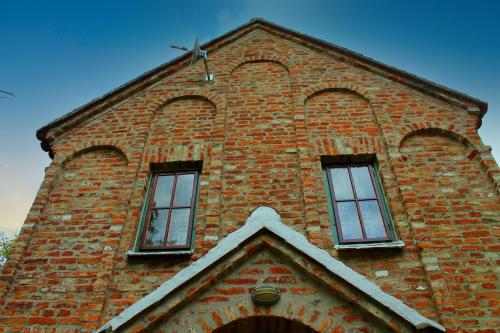 a tall brick building with three windows on it at Cserépmadár szállás és Csinyálóház in Velemér