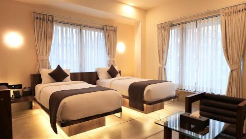 苏拉特De Glance Hotel, Near Surat Railway Station的带窗户的酒店客房内的两张床