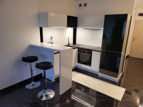 a kitchen with a counter and two stools in it at Apartamenty Potulicka Centrum in Szczecin