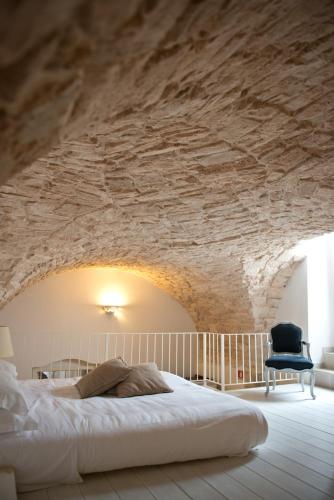 a bedroom with a bed and a stone wall at Hotel Corte Altavilla in Conversano
