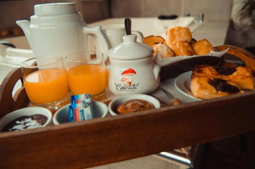 Una bandeja con comida para desayunar, zumo de naranja y bollería. en SUITES ALITHUÉ, en La Cumbrecita