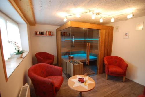 ヘルマゴルにあるHaus Martlの赤い椅子、テーブル、バスタブが備わる客室です。