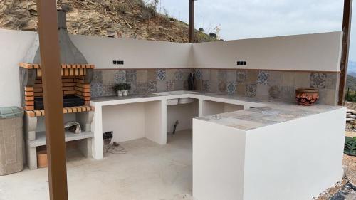 uma cozinha com um balcão branco e uma mesa em Casa Cuatro Vientos - Barranco Del Sol em Almogía