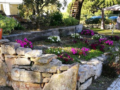una pared de piedra con flores en un jardín en Quinta Lagus Resort - Casa de Campo, en Palmela