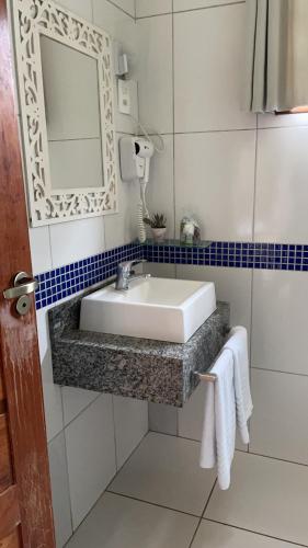 a bathroom with a sink and a mirror and towels at Pousada Villa Di Carpi in Monte Sião