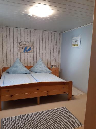 a bedroom with a wooden bed with blue pillows at Ferienwohnungen-im-Koog-2 in Wesselburenerkoog