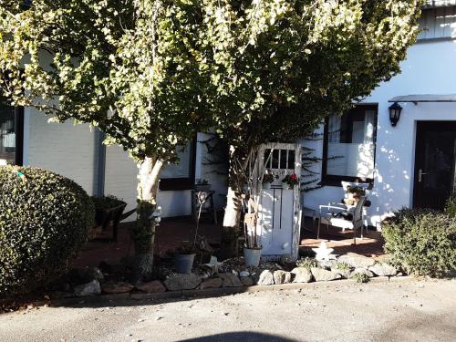 a white house with a tree and a door at Ferienwohnungen-im-Koog-2 in Wesselburenerkoog