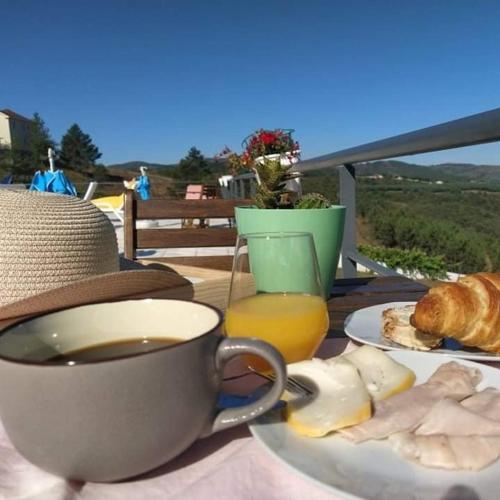 a table with a cup of coffee and a plate of food at Vivenda das Carvalhas in Amiar