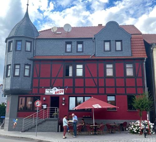 un edificio rojo con gente parada frente a él en Ferienwohnung in der schönen Rhön en Stadtlengsfeld