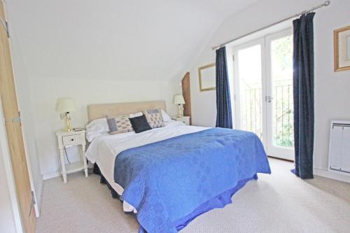 a bedroom with a bed and a large window at Grooms Cottage in Kent