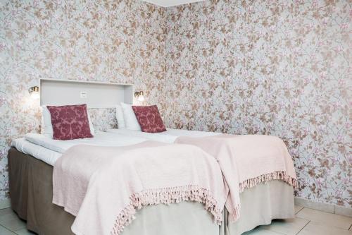two beds in a bedroom with floral wallpaper at Hotell och Restaurang Hovs Hallar in Båstad