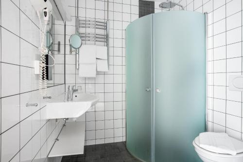 a bathroom with a sink, toilet, and shower stall at Hotell och Restaurang Hovs Hallar in Båstad