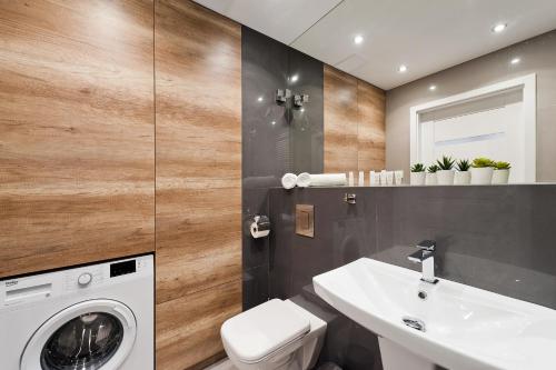 a bathroom with a washing machine and a sink at Central Apartments by Bed&Bath in Kraków