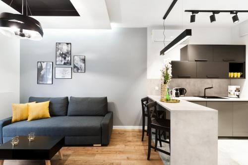 a living room with a blue couch and a kitchen at Central Apartments by Bed&Bath in Kraków