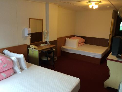 a small room with two beds and a television at Yeashow Villa in Fenchihu