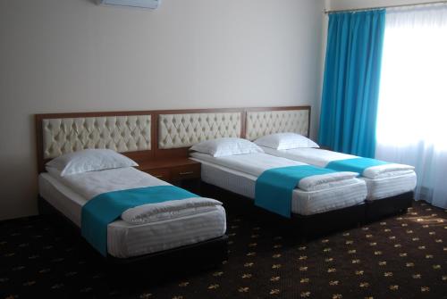 two beds in a hotel room with blue curtains at Hostel Paltinis in Hunedoara