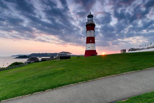 a red and white lighthouse sitting on top of a grass field at Hoe Park House, Sleeps 10, Historic, Central, Near Excellent Dining, Bars & Seafront in Plymouth