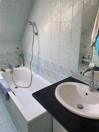 une salle de bain avec un lavabo, une baignoire et un miroir dans l'établissement CHAMBRE Cosy, à Nandy