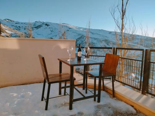 a table and chairs on a balcony with a view at APARTAMENTO LOS VALLES en SIERRA NEVADA Parking gratuito in Sierra Nevada