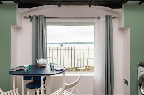 a table with chairs and a window with a view of the water at For Sea Lovers ! Coastguard Boat House right on Belfast Lough in Newtownabbey