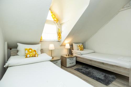 two beds in a attic bedroom with white walls at Dobó Vendégház in Eger