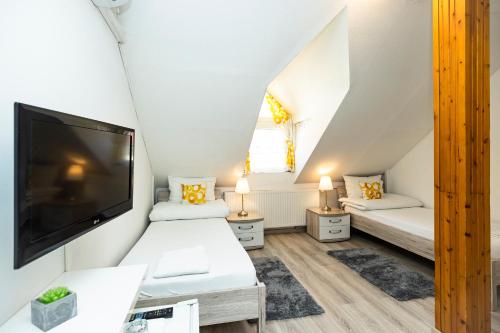 a small attic bedroom with two beds and a flat screen tv at Dobó Vendégház in Eger