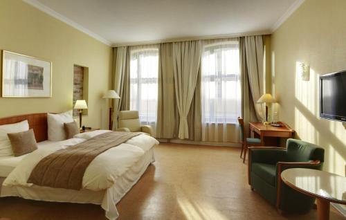 ヴィスマールにあるFründts Hotelのベッド、デスク、テレビが備わるホテルルームです。
