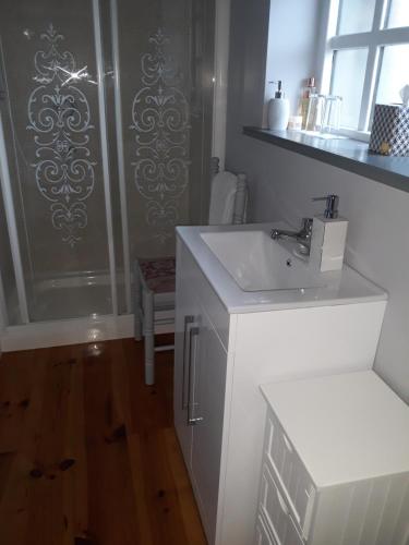 a white bathroom with a sink and a shower at Mill Lane in Buncrana