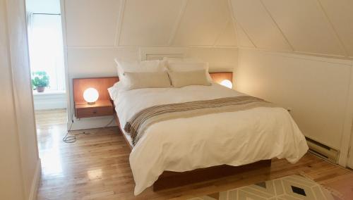 um quarto com uma grande cama branca e 2 candeeiros em Napier House em Campbellton