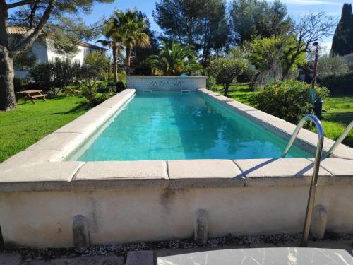 a swimming pool with blue water in a yard at Le poisson qui recule - Maison et piscine dans parc arboré proche mer in Sanary-sur-Mer