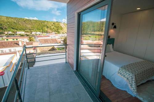 a balcony with a bed and a view of a city at Apartamentos da Travessa in Praia da Vitória